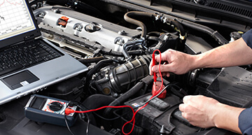 Auto mechanic using a digital diagnostic tool to pinpoint what is wrong with a car engine