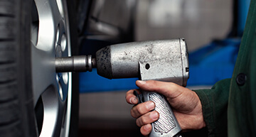 Mechanic using a lug gun to remove the lug nuts on a tire
